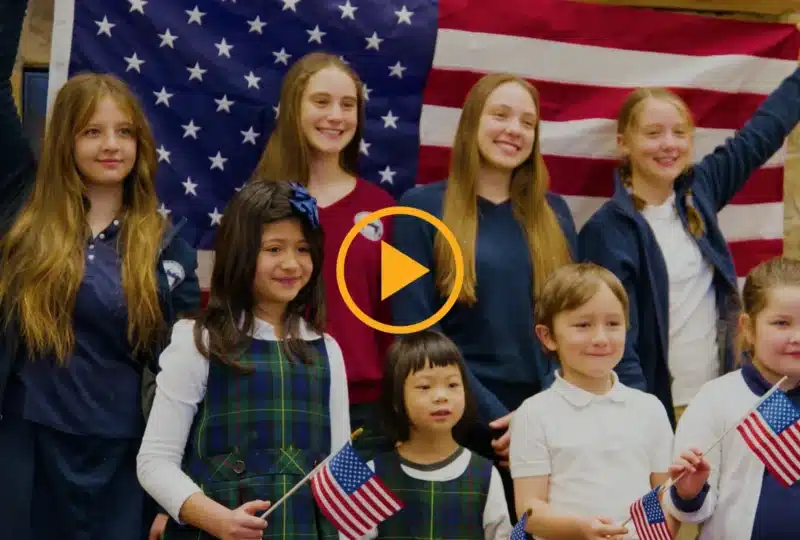Group of children posing in front of a large U.S. flag